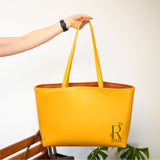 Close-up of a yellow leather tote bag with personalized initials