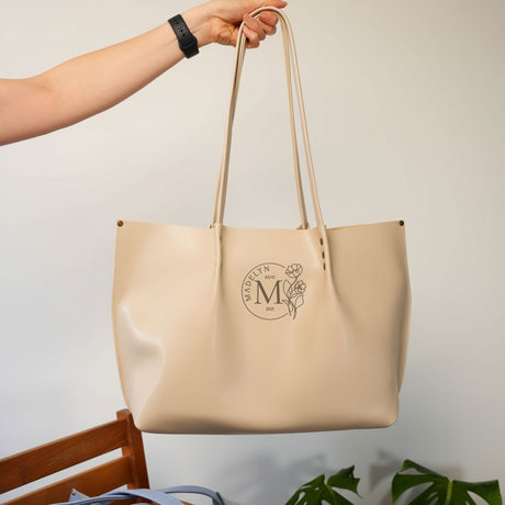 a person holding a beige bag with a monogrammed m on it