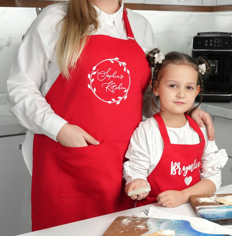 a woman and a little girl in red aprons