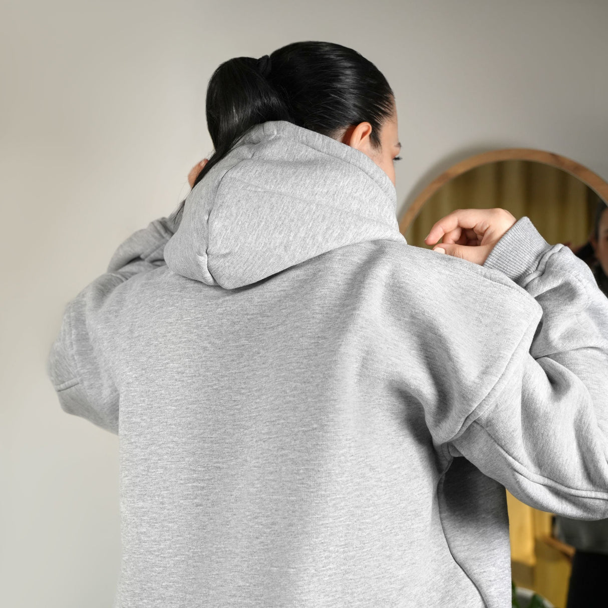 a woman standing in front of a mirror wearing a gray hoodie