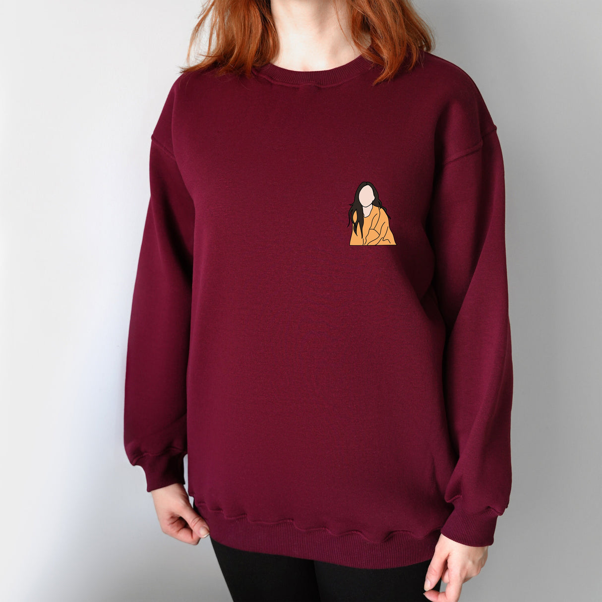 a woman with red hair wearing a maroon sweatshirt with a picture of a woman on