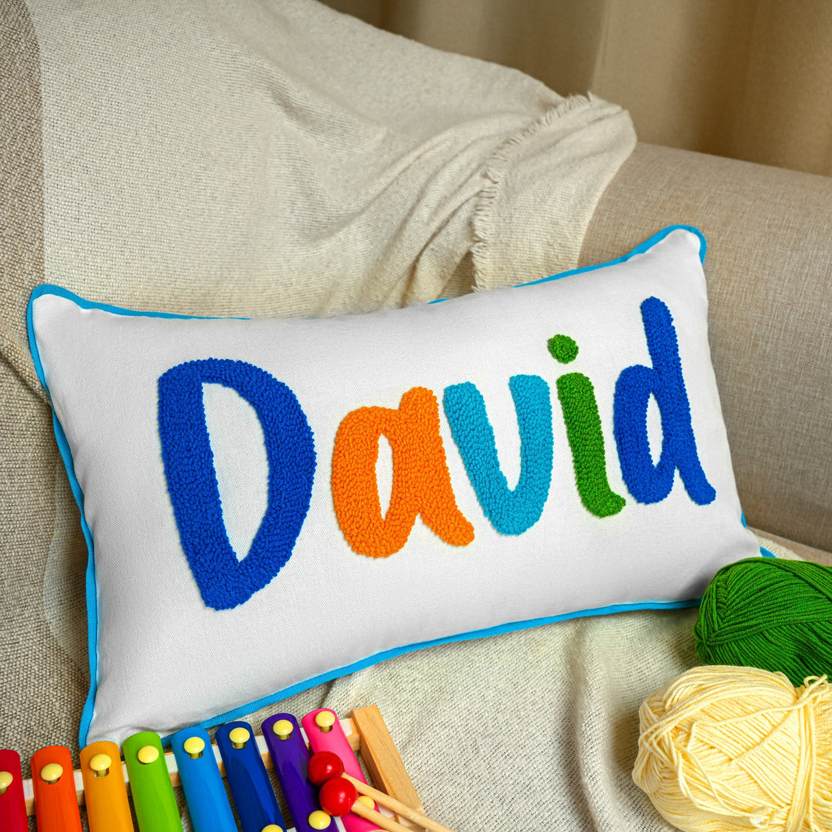 a white pillow with the word david on it next to crochet hooks and