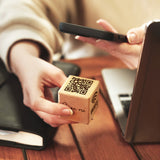 a person holding a wooden block with a qr code on it