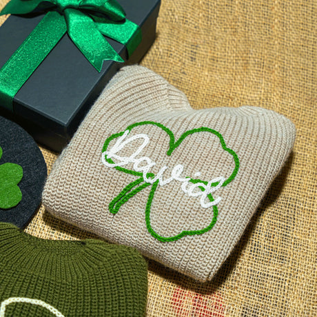 a hat, sweater, and sweater sitting next to a gift box