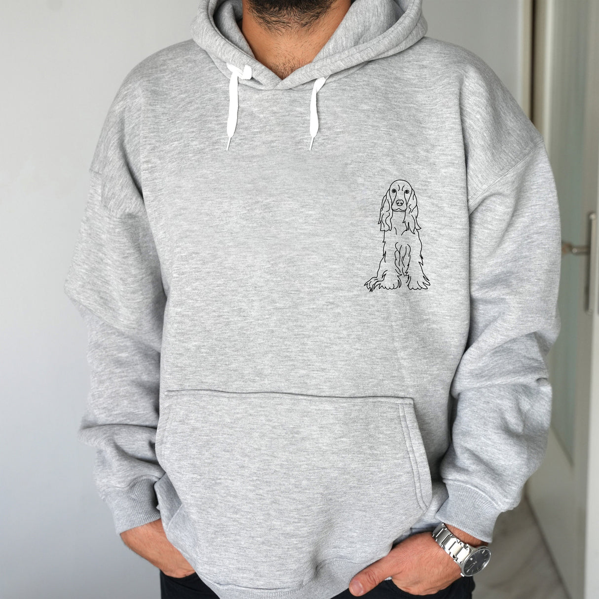 a man wearing a grey hoodie with a dog drawn on it