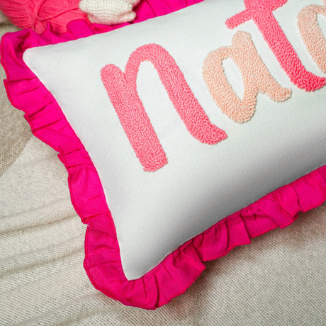 a pink and white pillow sitting on top of a bed