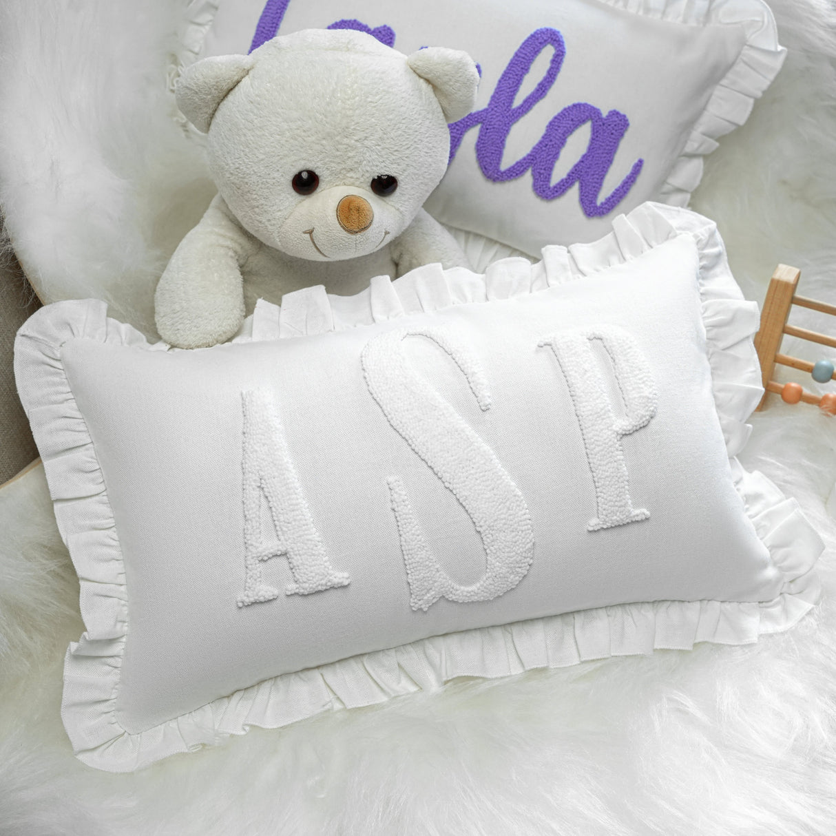a white teddy bear sitting on top of a pillow