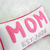 a pink and white pillow with the word mom on it