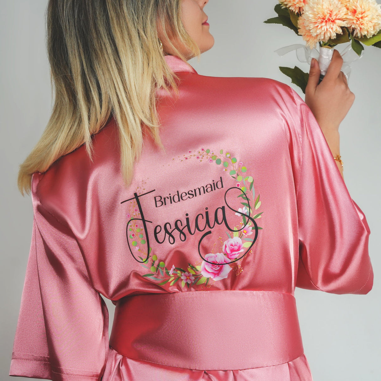 a woman in a pink robe holding a bouquet of flowers