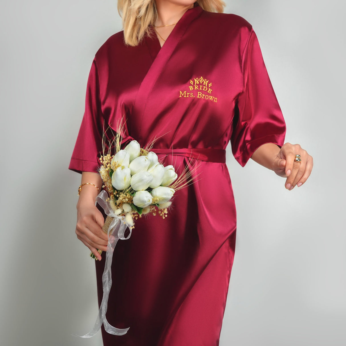 a woman in a red robe holding a bouquet of flowers