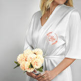 a woman in a white robe holding a bouquet of flowers