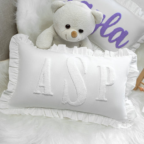 a white teddy bear sitting next to a pillow