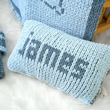 a blue knitted pillow sitting on top of a white rug