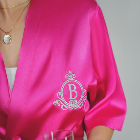 a woman in a pink robe holding a wine glass