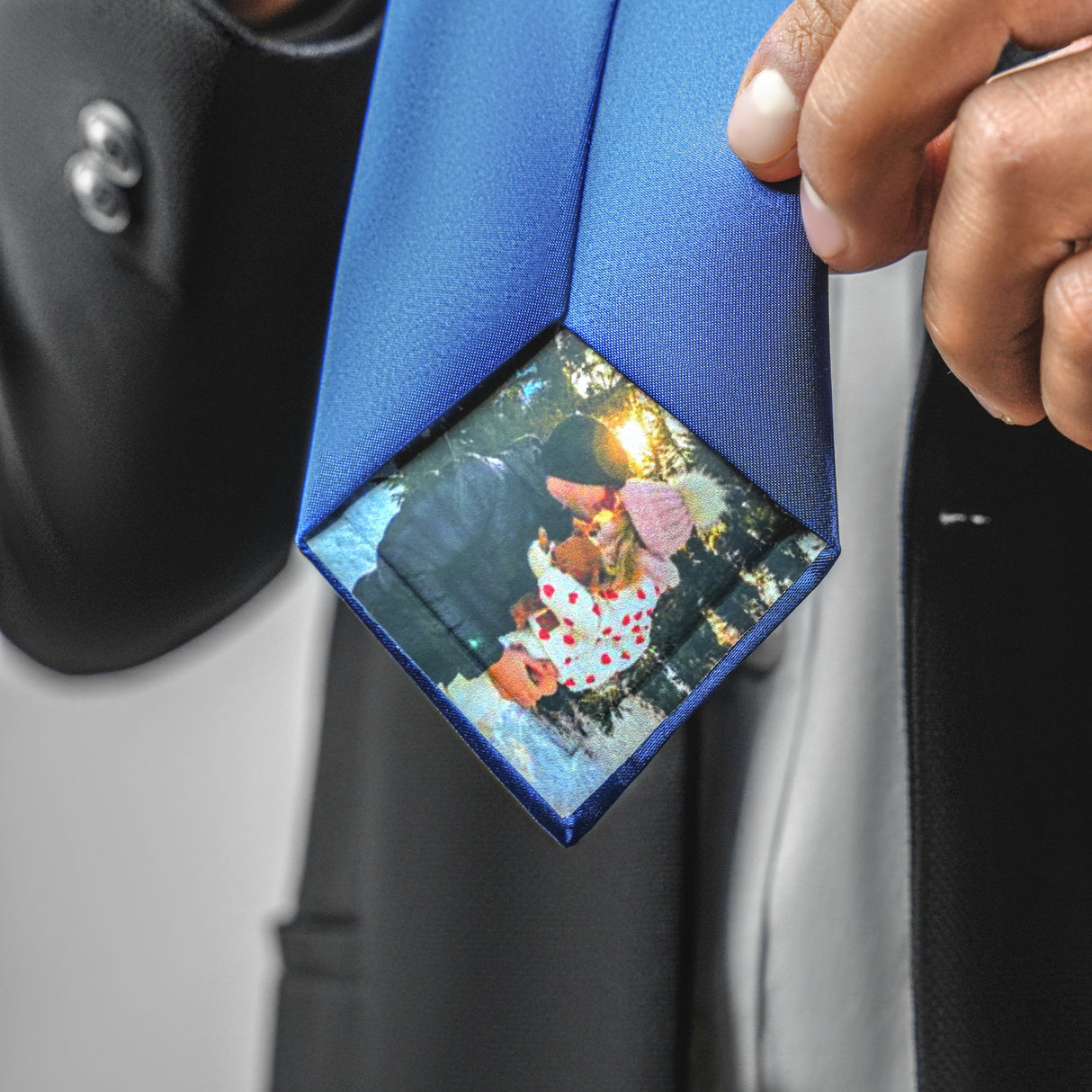 a man wearing a blue tie with a picture hanging from it