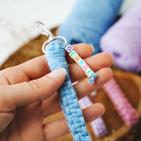 a person holding a blue keychain with the word peace written on it