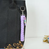 a purple keychain hanging from a black bag