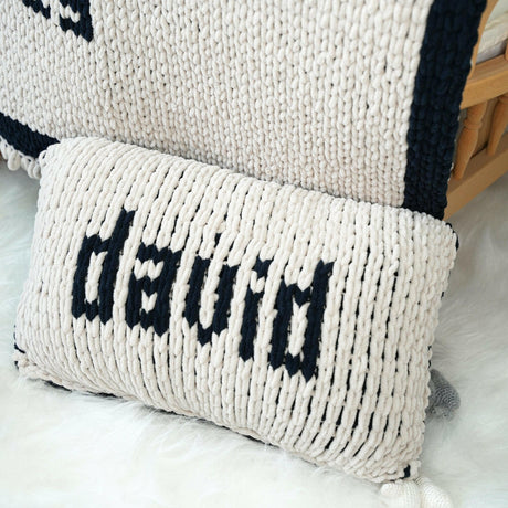 a close up of a knitted pillow on a bed