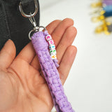 a person holding a purple keychain with letters on it