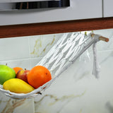 a white hammock filled with fruit on top of a counter