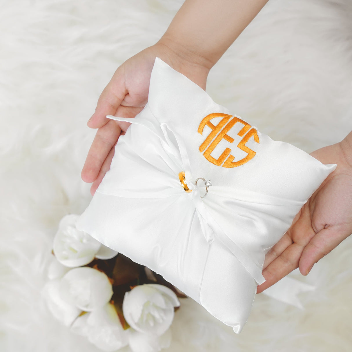 a person holding a pillow with a monogrammed bow on it