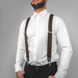 a man wearing a white shirt and brown suspenders