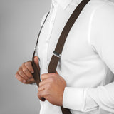 a man wearing a white shirt and brown suspenders