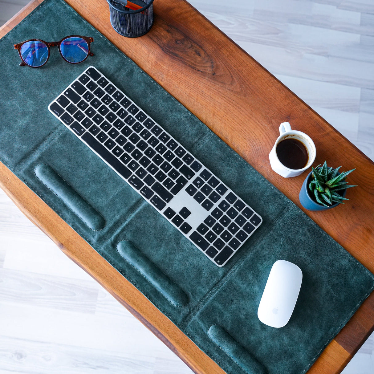 a desk with a keyboard, mouse and sunglasses on it