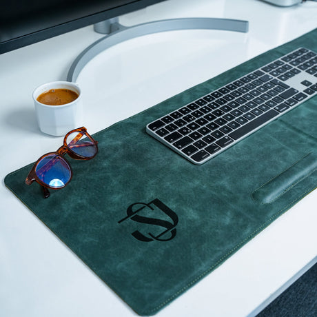 a desk with a keyboard, sunglasses and a cup of coffee