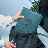 a person holding a green book in front of a laptop