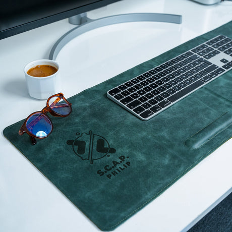 a computer keyboard, sunglasses, and cup of coffee on a desk