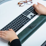 a person typing on a computer keyboard with glasses on top of it