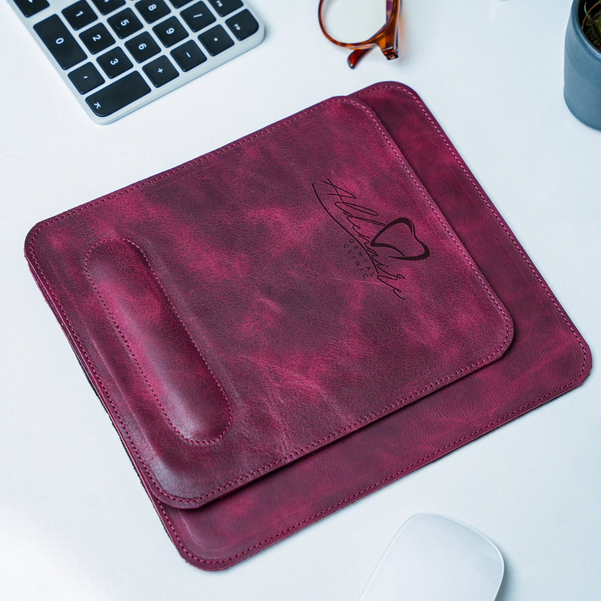 a leather mouse pad sitting on top of a desk next to a keyboard