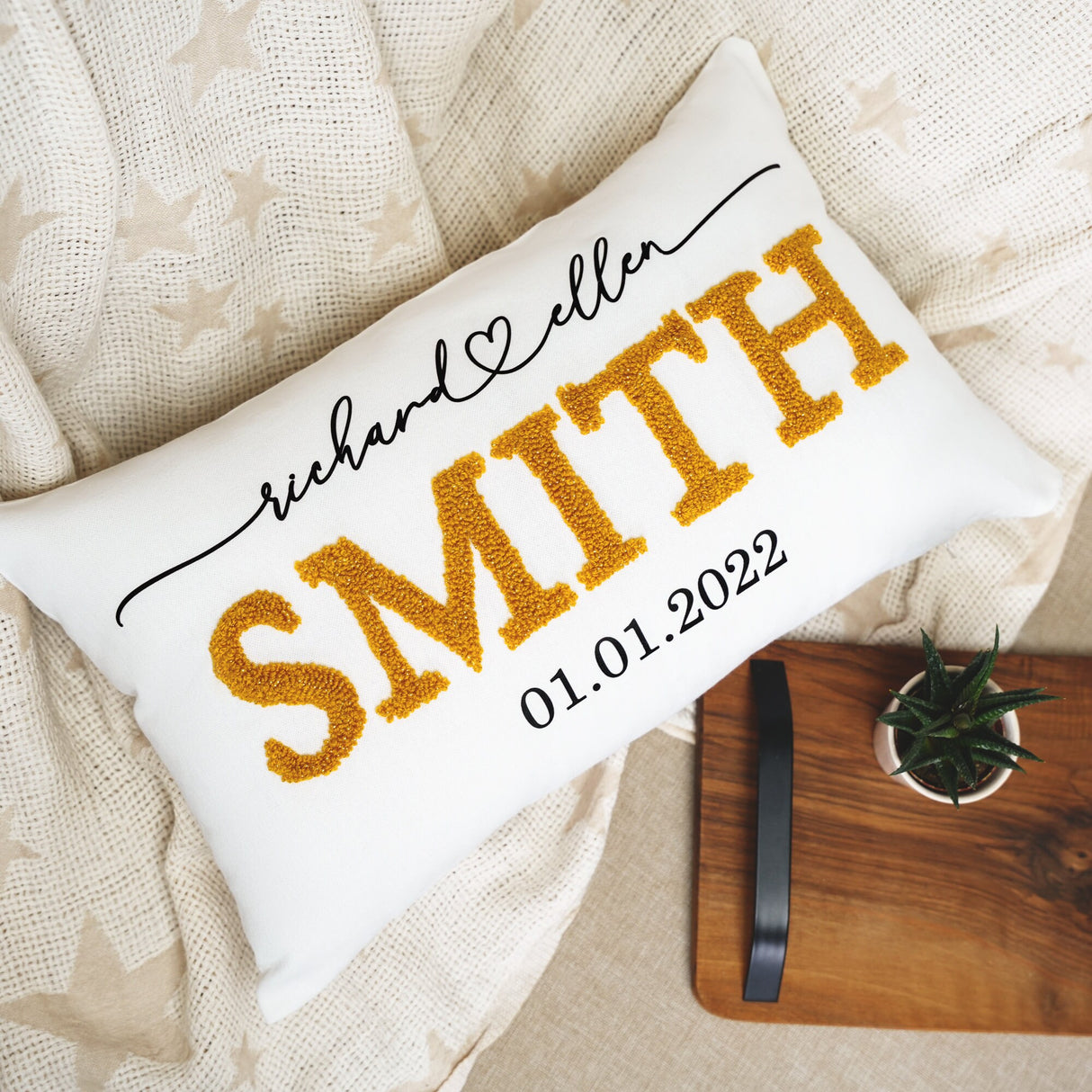 a personalized pillow on a bed next to a potted plant