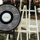 a large black and white sign sitting on top of a grass covered field