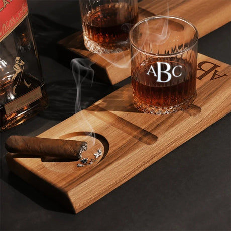 a cigar and a glass of whiskey on a wooden tray