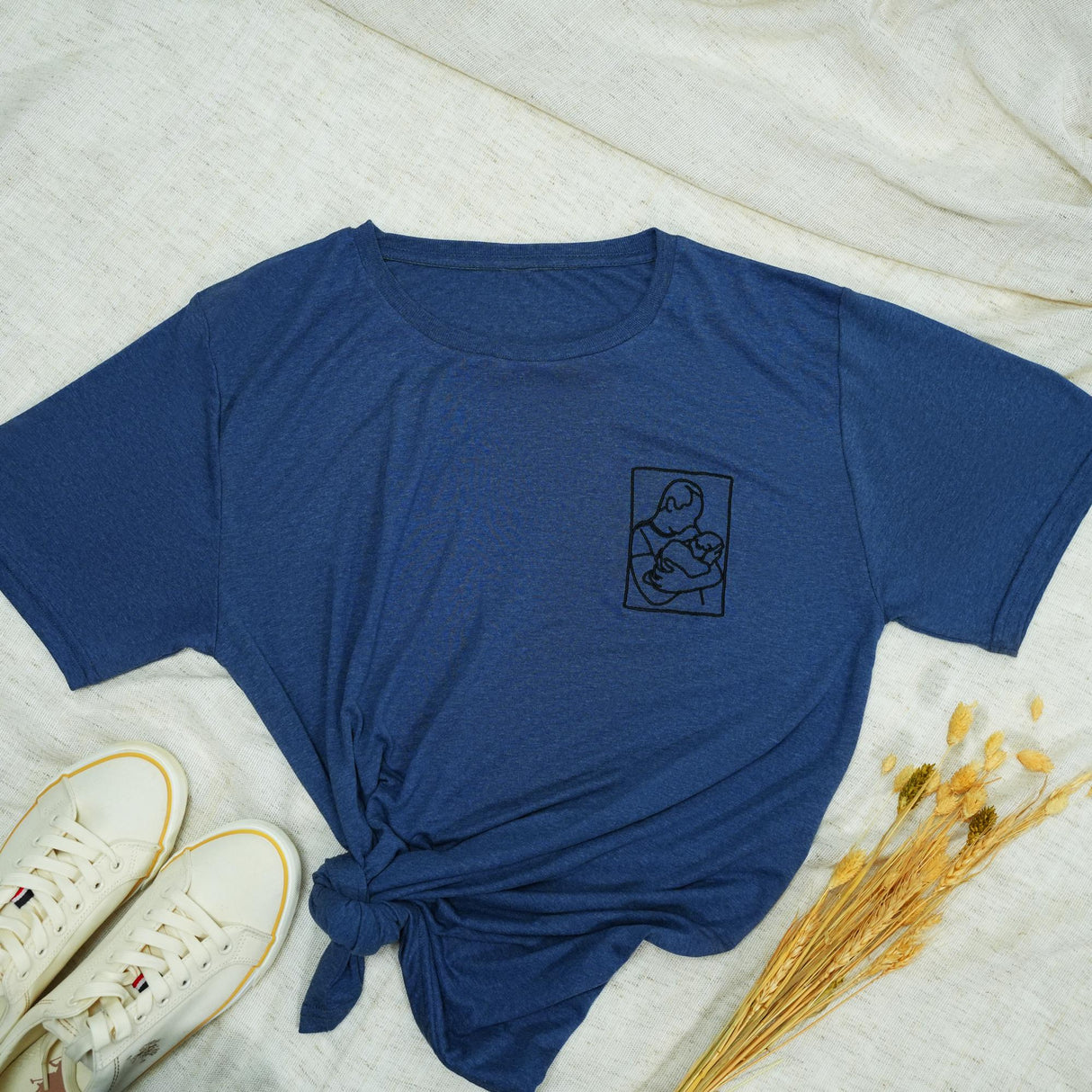 a blue t - shirt with a picture of a person holding a baby on it