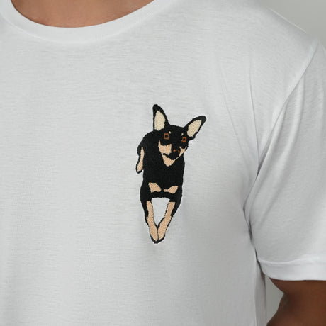 a man wearing a white t - shirt with a black and tan dog embroidered on