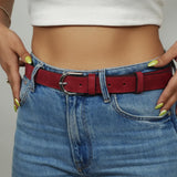 a woman wearing a red belt and jeans