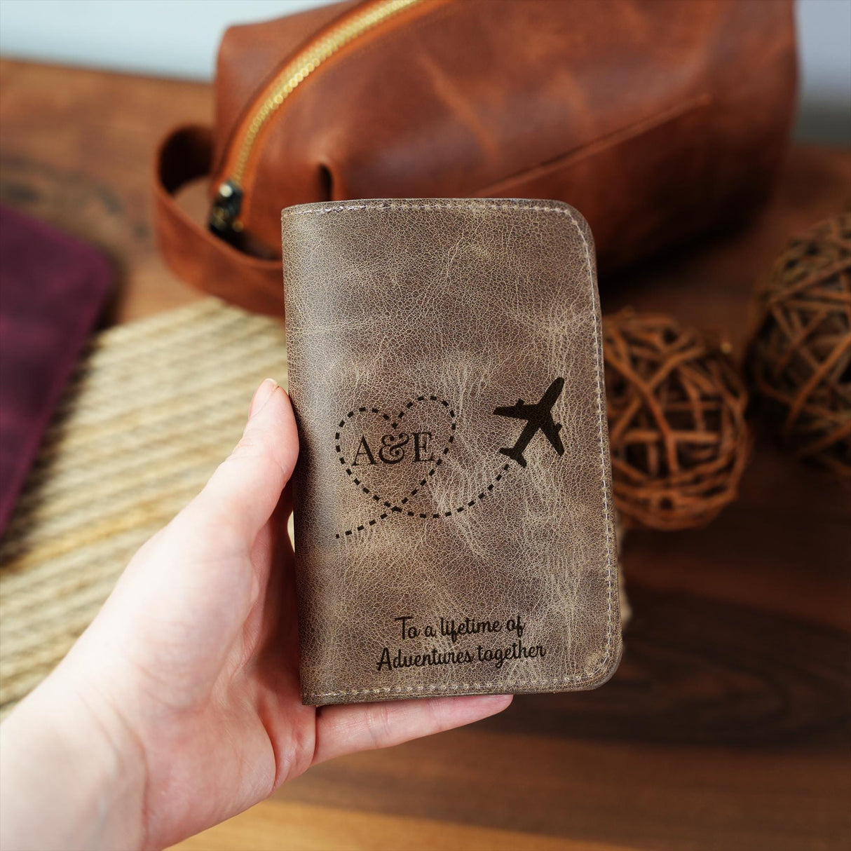 a hand holding a brown leather wallet with an airplane on it