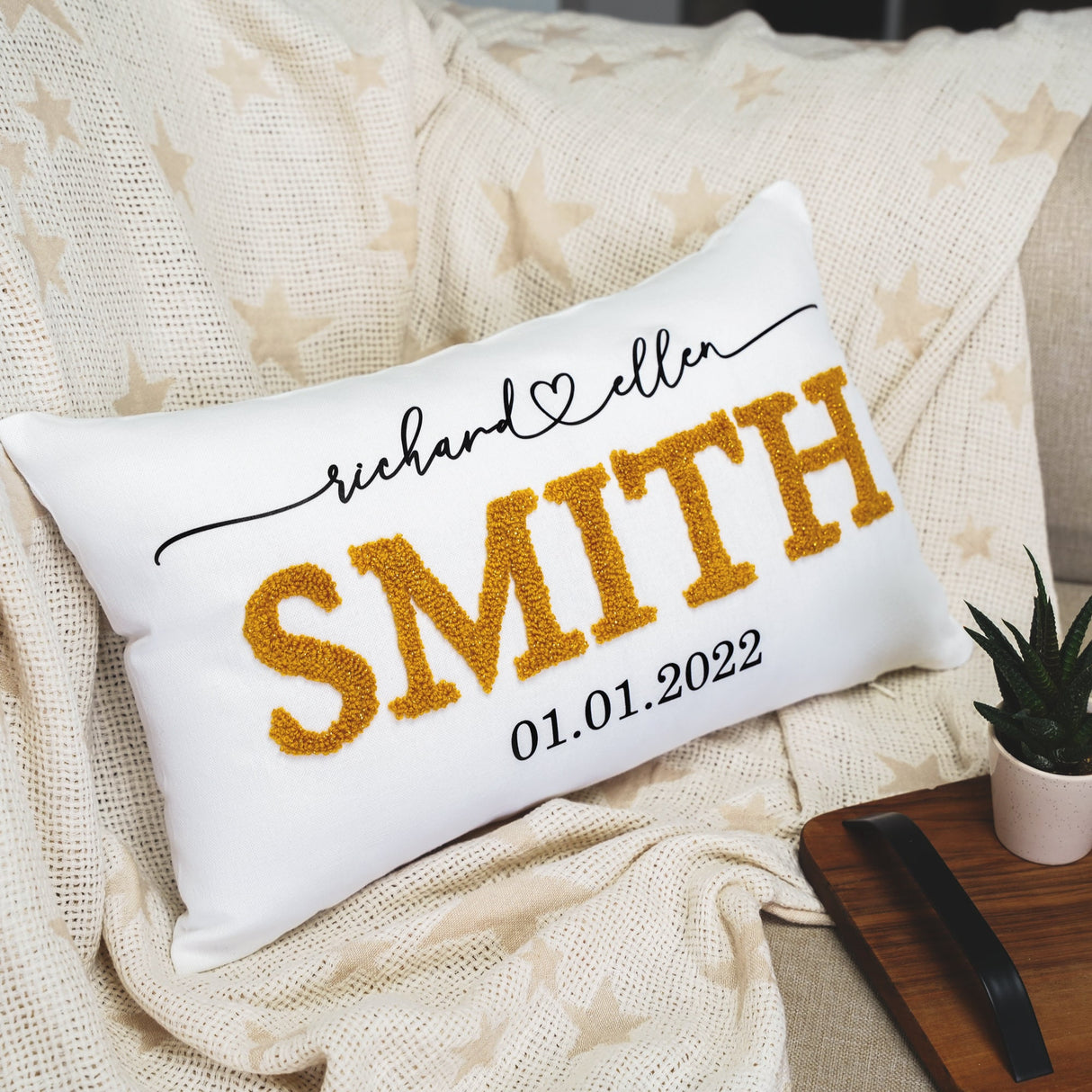 a personalized pillow sitting on a couch next to a potted plant