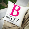 a white pillow with a pink b on it