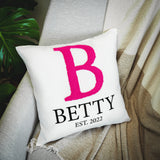 a white pillow with a pink b on it