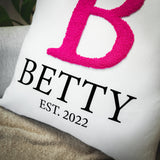 a white pillow with a pink letter on it