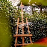 a wooden easel sitting in front of a bush