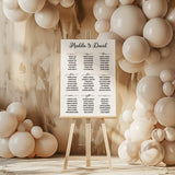 a wedding seating chart on a easel surrounded by balloons