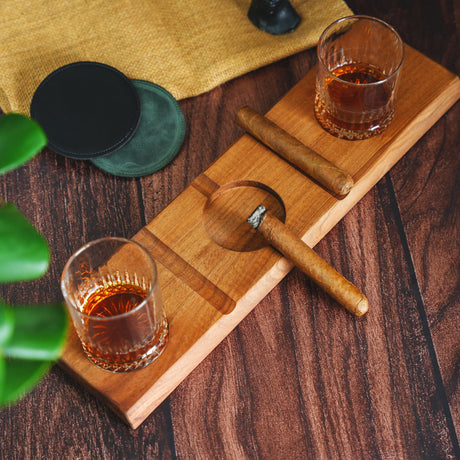 a wooden cutting board topped with two glasses of whiskey