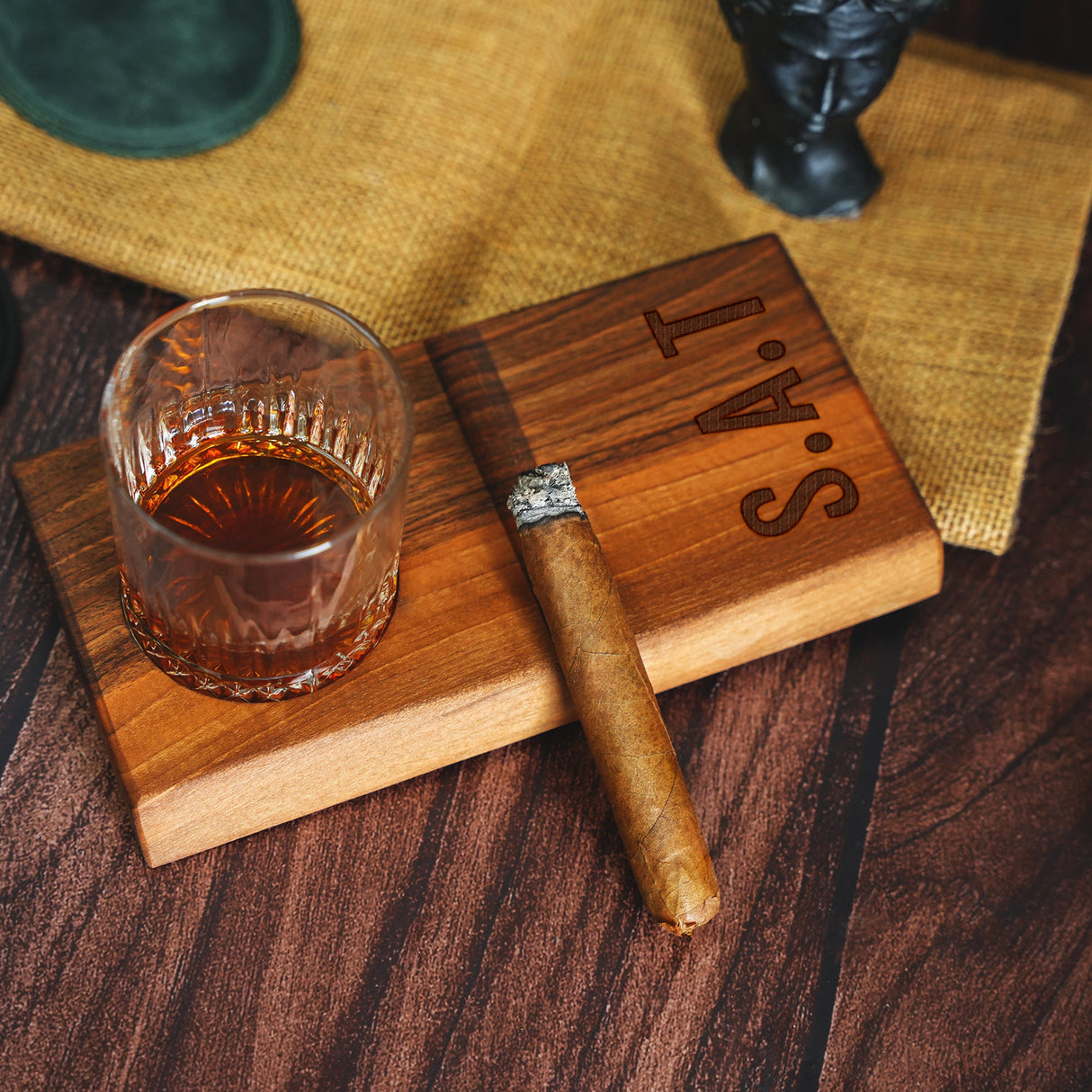 a cigar sitting on top of a wooden cutting board next to a glass