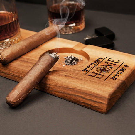 a cigar sitting on a cutting board next to a glass of whiskey