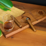 a wooden cutting board with a glass of whiskey on it